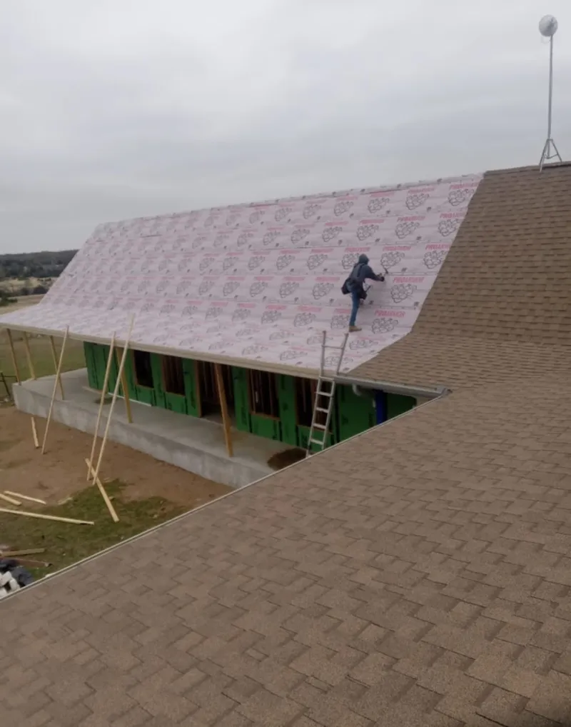Worker preparing underlayment for a metal roof installation in Council Bluffs